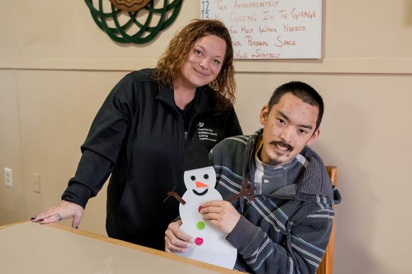 A Direct Service Provider/Caregiver at Homes for Independent Living posing with a client